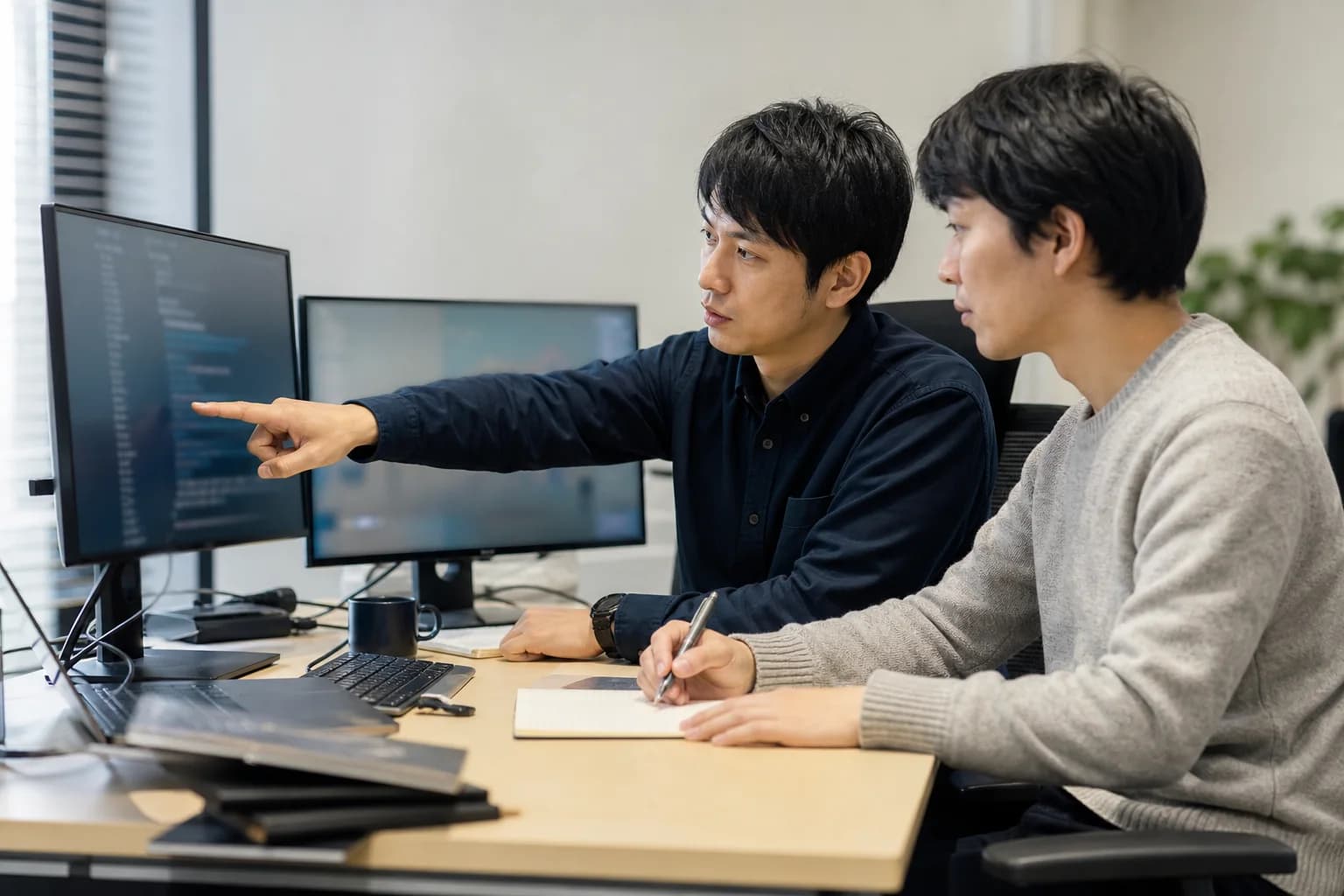 開発中のシステムを複数人でレビューするエンジニア